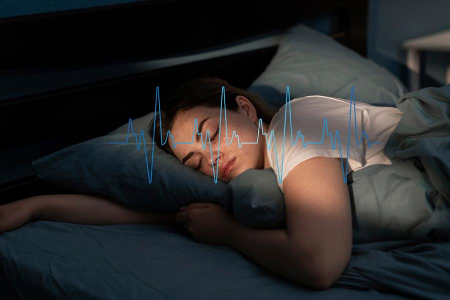 A person sleeps with her head on a pillow. A graphic of a heart beat is shown.