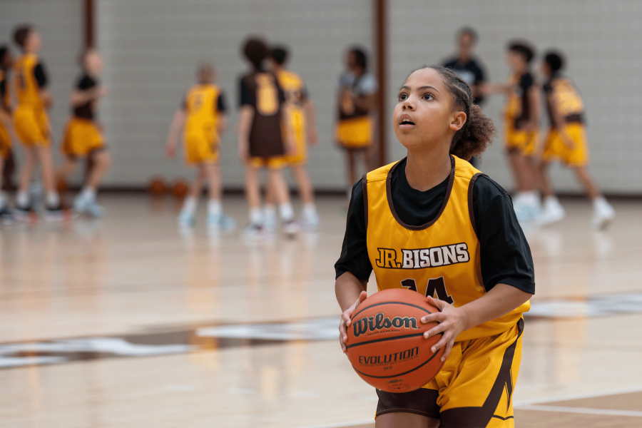 A girl lines up to take a shoot in a high performance basketball camp.