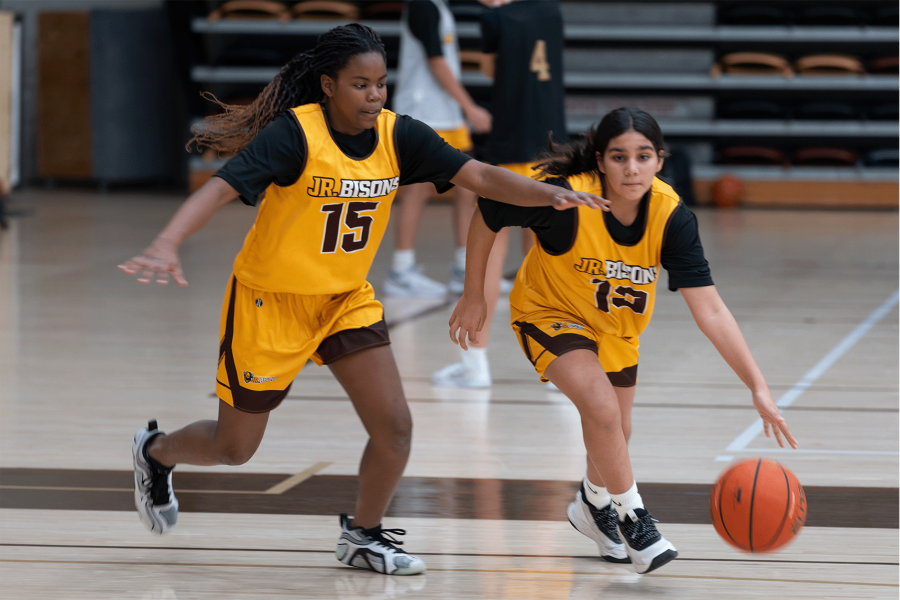 Two girls playing basketball during a Junior Bisons practice.