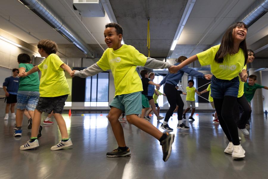Children hold hands in a circle facing outwards.