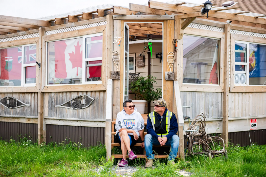 Two people sitting on the front step of the home.
