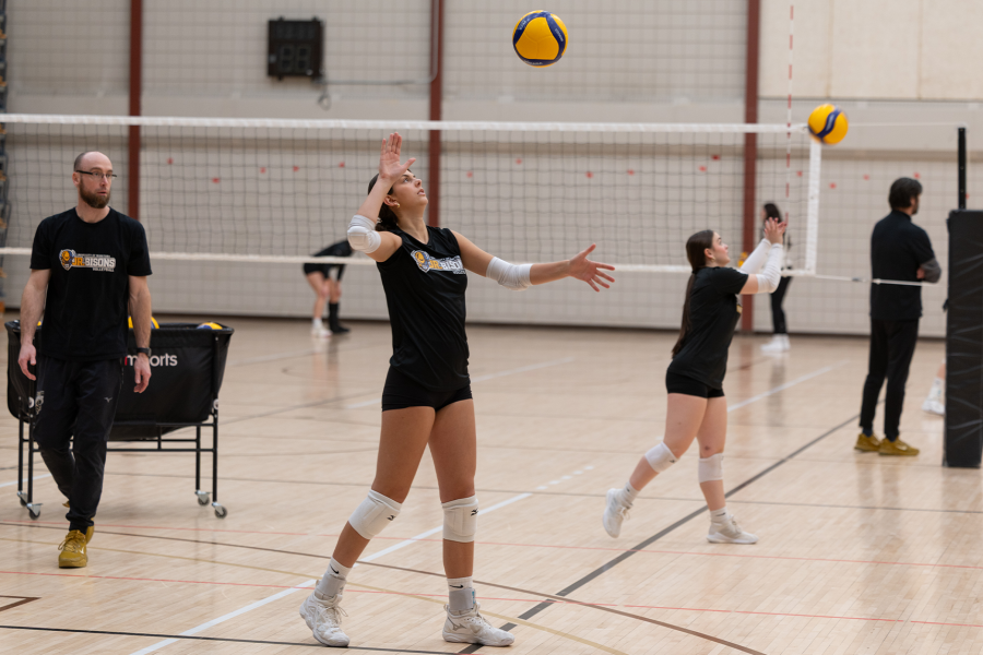 Girls practice serving a volleyball in a Junior Bisons practice.
