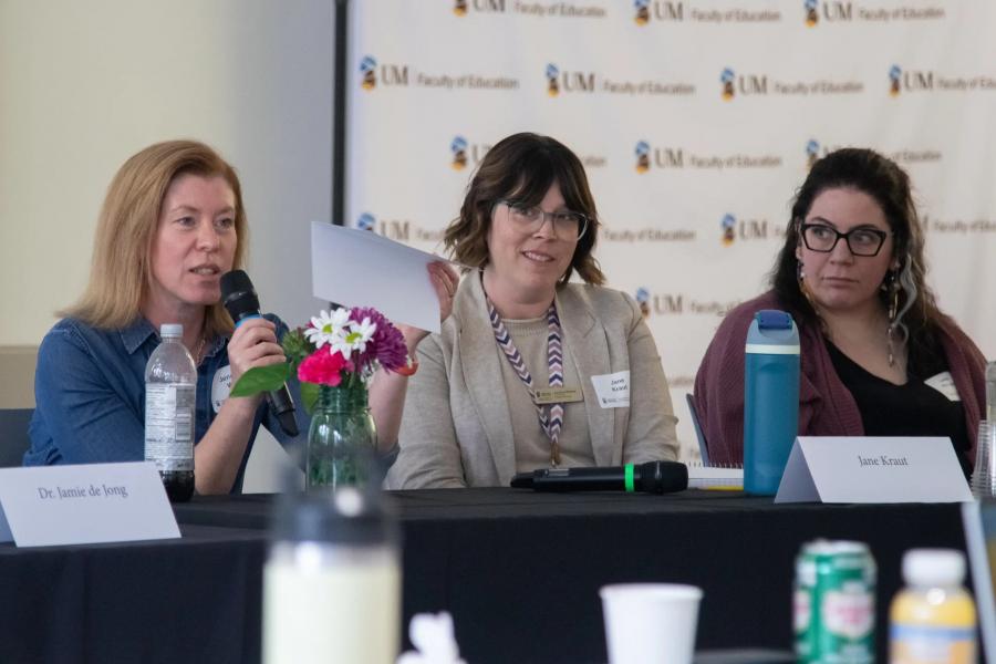 Three people sit at table at a conference