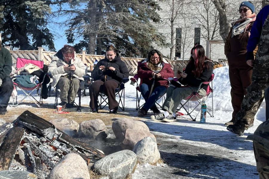 A group of people making fish skin leather at the UM Sweat Lodge site.