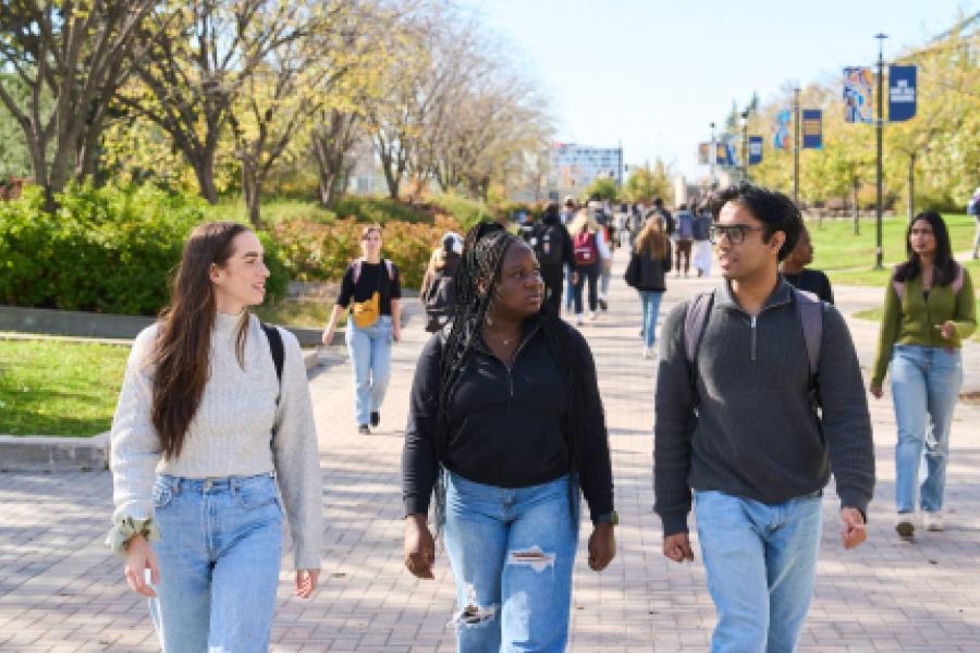 Three students walking together with more students behind them.