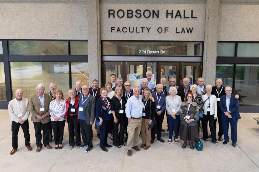 Law Class of 1976 with spouses standing at entrance of Robson Hall