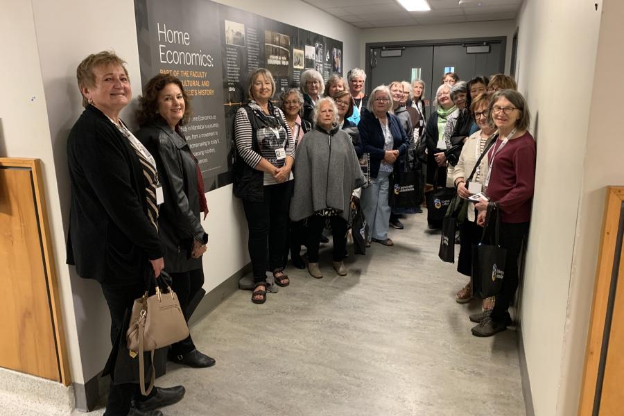 Human Ecology Class of 1976 50th reunion participants posing in front of Home Economics mural