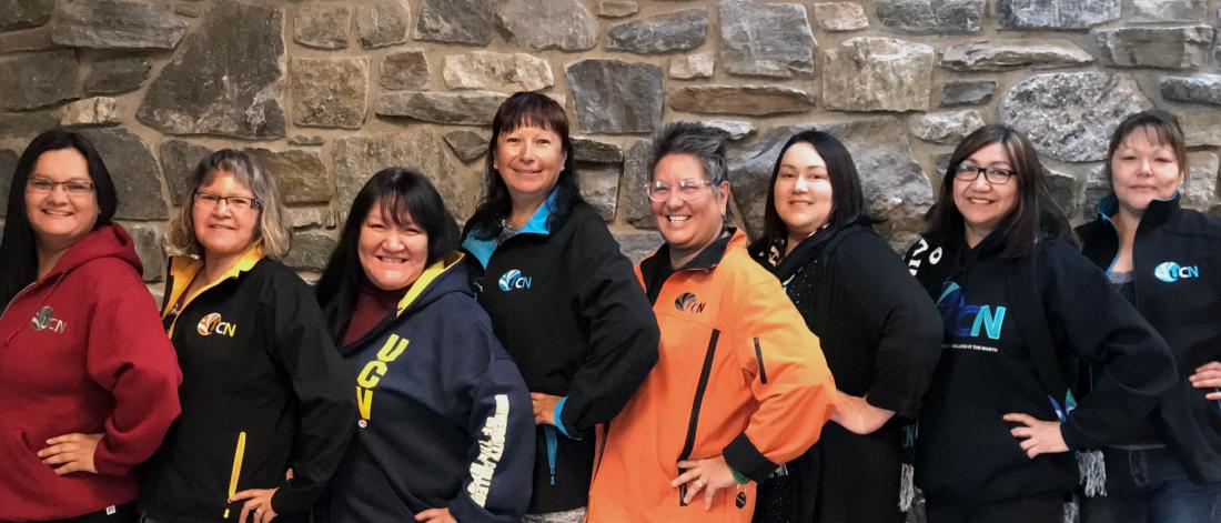 Eight faculty of social work alumnae stand together side by side smiling.