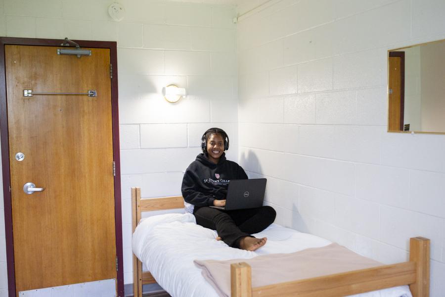 Female student laying on her bed with a laptop on her lap