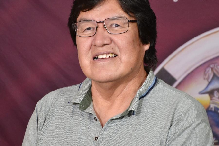 Stewart Hill in a grey top in front of a red backdrop