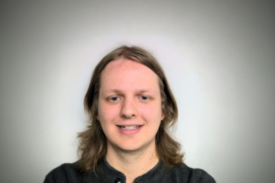 Nick Schroeder smiling with grey background