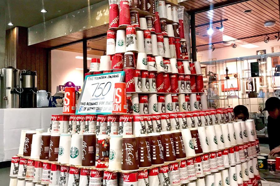A pyramid made of 750 disposable cups displayed with a sign that says they account for only 8% of the University of Manitobas daily cup use.